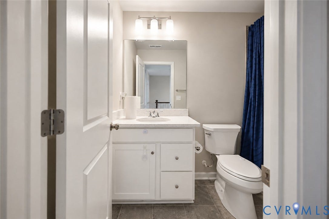 500 Rivanna Hill Way, Glen Allen, VA 23060 Bathroom featuring a white vanity with stone-composite countertop, undermount sink, three-light fixture, and stone-finish tile flooring