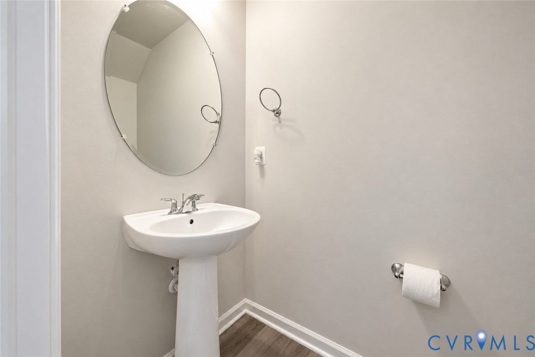 500 Rivanna Hill Way, Glen Allen, VA 23060 White pedestal sink with chrome faucet, oval frameless mirror, and wood-finish flooring