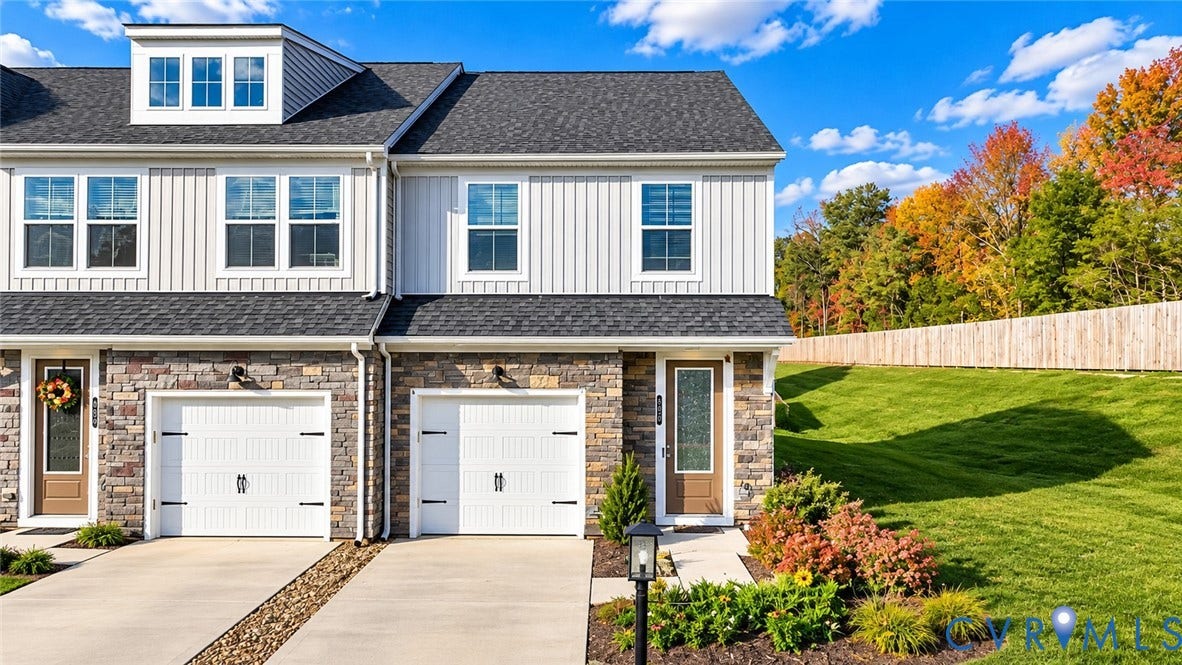 500 Rivanna Hill Way, Glen Allen, VA 23060 Townhome exterior featuring stone masonry, board-and-batten siding, a dormer window, dual-car garages, and an expansive grass lawn