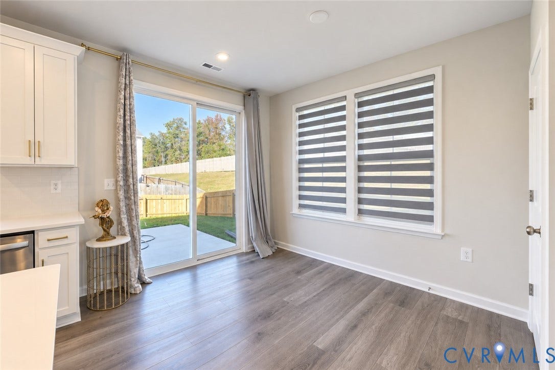 500 Rivanna Hill Way, Glen Allen, VA 23060 Wood-finish flooring, white shaker-style cabinetry with brass-tone hardware, and a sliding glass door opening to a concrete patio