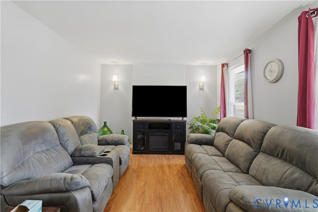 16401 Anderson Drive, Disputanta, VA 23833 Living area featuring wood-finish flooring, two wall-mounted sconces, and a textured accent wall