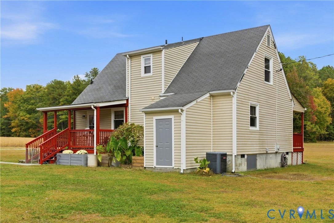 16401 Anderson Drive, Disputanta, VA 23833 Two-story residence featuring light-colored horizontal siding, a gabled roofline, an expansive covered porch with red railings, and an integrated exterior storage unit