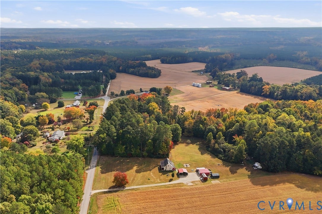 16401 Anderson Drive, Disputanta, VA 23833 Aerial perspective of expansive acreage featuring mature woodland, open pastures, multiple outbuildings, and paved road access