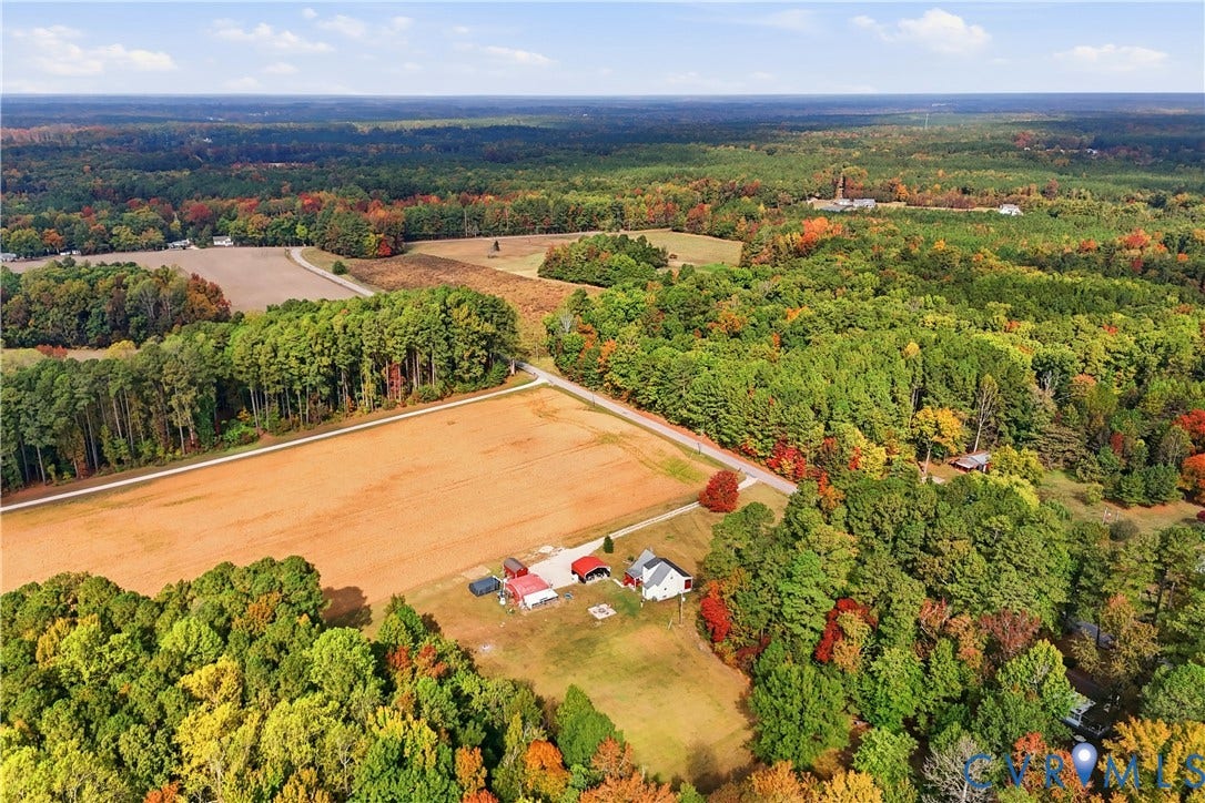 16401 Anderson Drive, Disputanta, VA 23833 Aerial perspective of a multi-acre property featuring open pasture land, multiple outbuildings, and extensive surrounding woodland