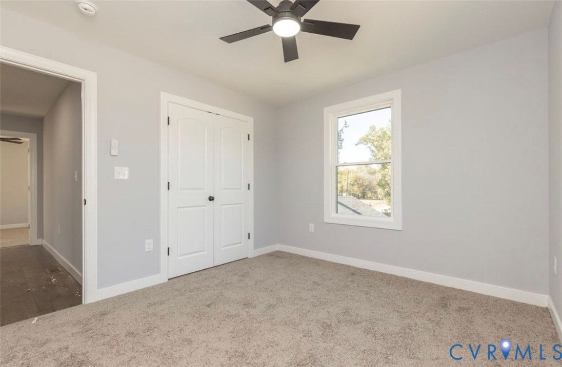 25604 Greensville Avenue, West Petersburg, Dinwiddie, VA 23803 Neutral-toned interior space featuring neutral wall-to-wall carpeting, double-panel closet doors, a multi-pane window, and a ceiling-mounted light fixture with an integrated fan