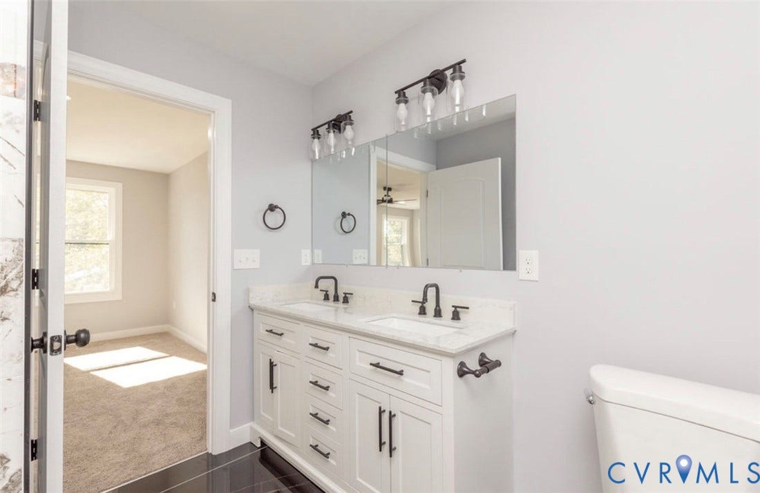 25604 Greensville Avenue, West Petersburg, Dinwiddie, VA 23803 Double vanity featuring white cabinetry, stone-finish countertops, undermount sinks, matte black hardware, and wall-mounted lighting