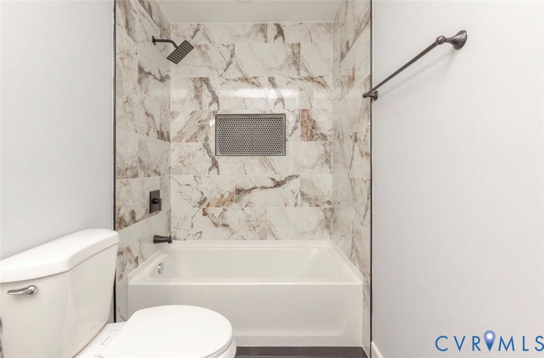 25604 Greensville Avenue, West Petersburg, Dinwiddie, VA 23803 Full-height tile surround with a marbled pattern, integrated shower niche, matte black rainfall showerhead, matte black hardware, and an alcove soaking tub