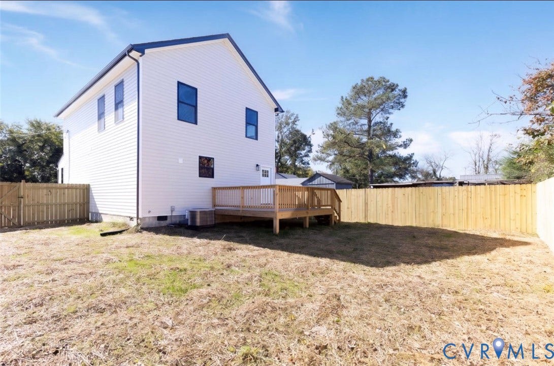 25604 Greensville Avenue, West Petersburg, Dinwiddie, VA 23803 Rear exterior featuring light-toned horizontal siding, a wood deck, and a full-height privacy fence enclosing the yard