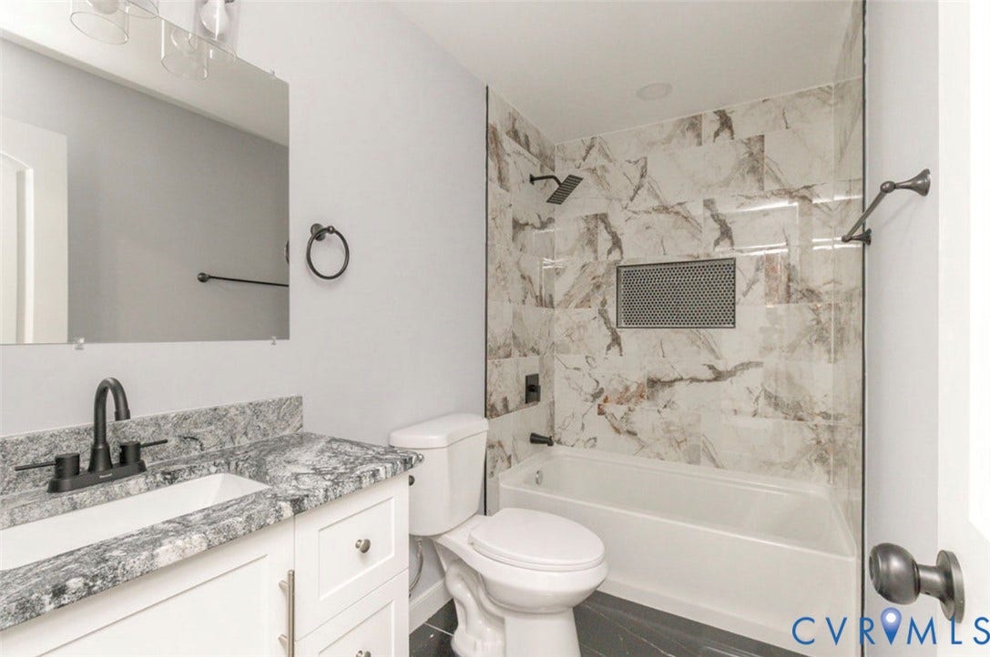 25604 Greensville Avenue, West Petersburg, Dinwiddie, VA 23803 Bathroom featuring stone-patterned vanity countertop, white cabinetry, matte black hardware, and tub surround with decorative tile inlay