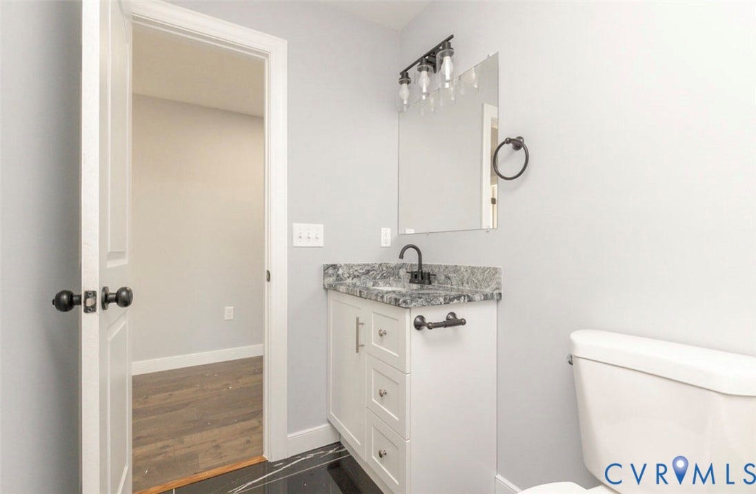 25604 Greensville Avenue, West Petersburg, Dinwiddie, VA 23803 White cabinetry vanity with stone-finish countertop, undermount sink, matte black faucet, wall-mounted light fixture, and black floor tile