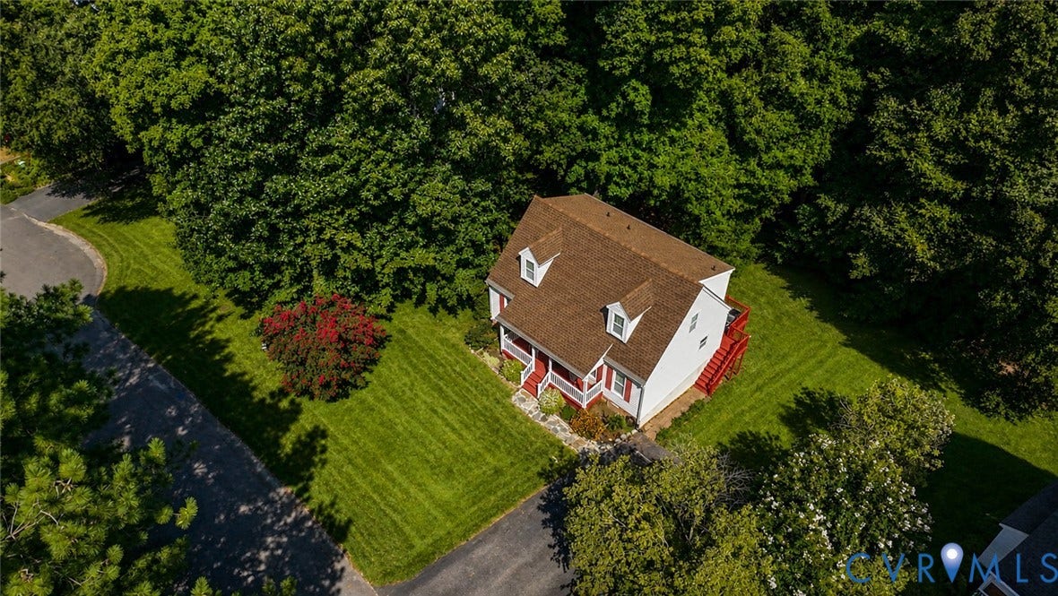 10208 Claybar Trail, Chesterfield, VA 23236 Two-story residence featuring a shingled roof, dual dormer windows, a stone-paved walkway, and a rear elevated deck, all situated on a lot with mature trees and maintained lawn