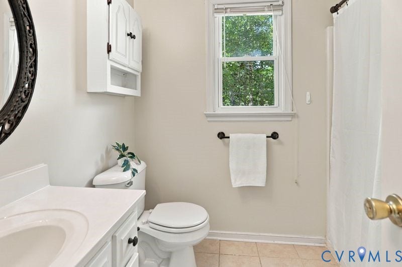 10208 Claybar Trail, Chesterfield, VA 23236 Bathroom featuring a white vanity cabinet with a solid surface countertop, an oval wall-mounted mirror, a matching upper storage cabinet, and a window with a neutral tile floor