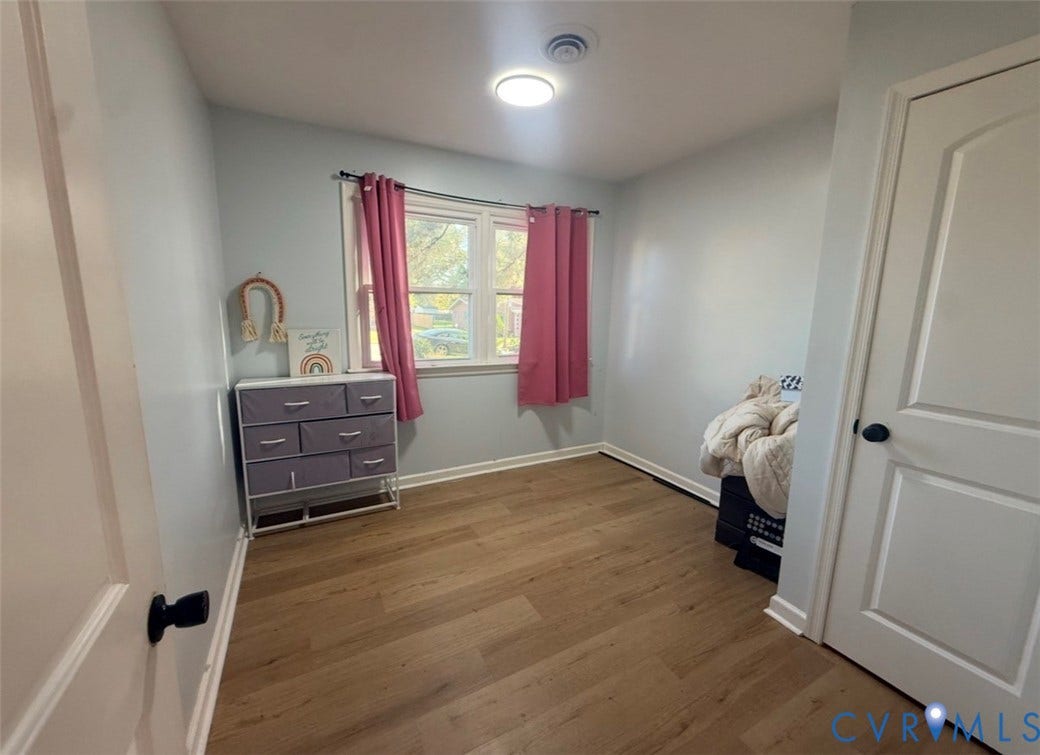 Room featuring wood-finish flooring, a dual-pane window, and a paneled interior door with a matte black handle