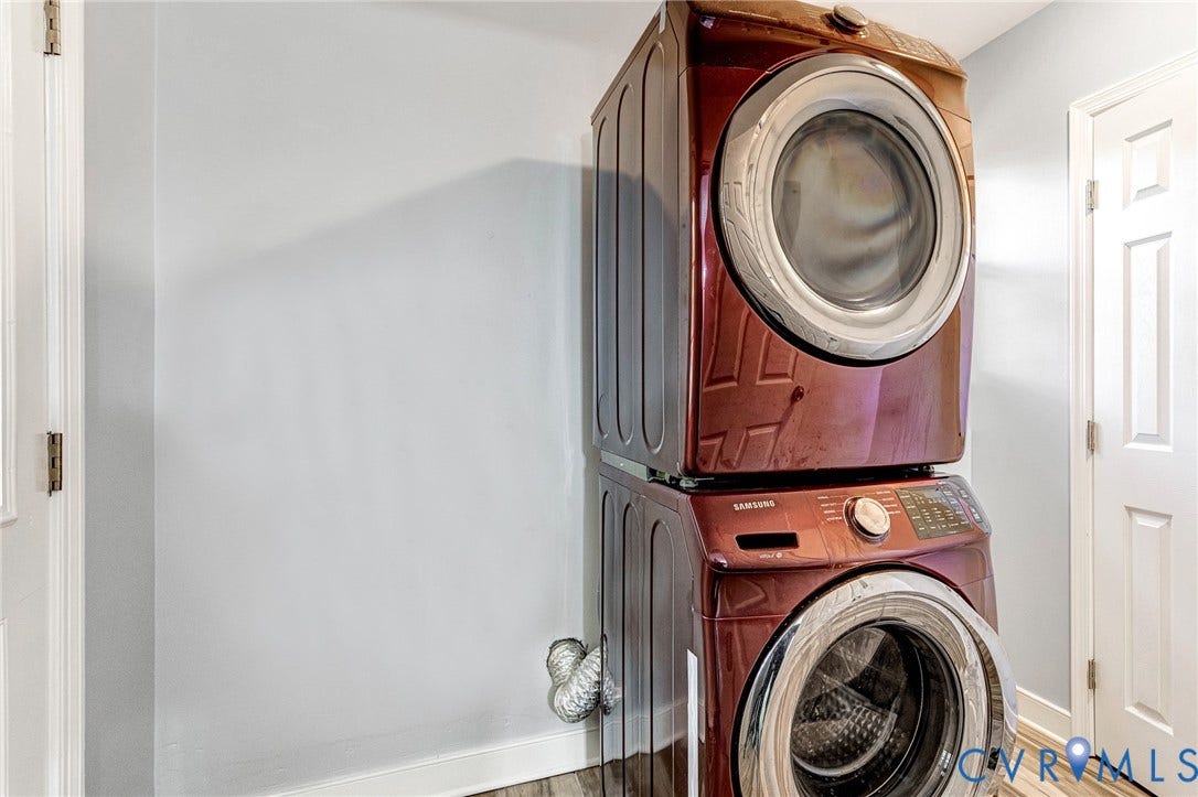 7304 Bowler Street, Henrico, VA 23228 Stacked, front-loading laundry appliances with a high-gloss finish, multi-panel doors, and wood-finish flooring