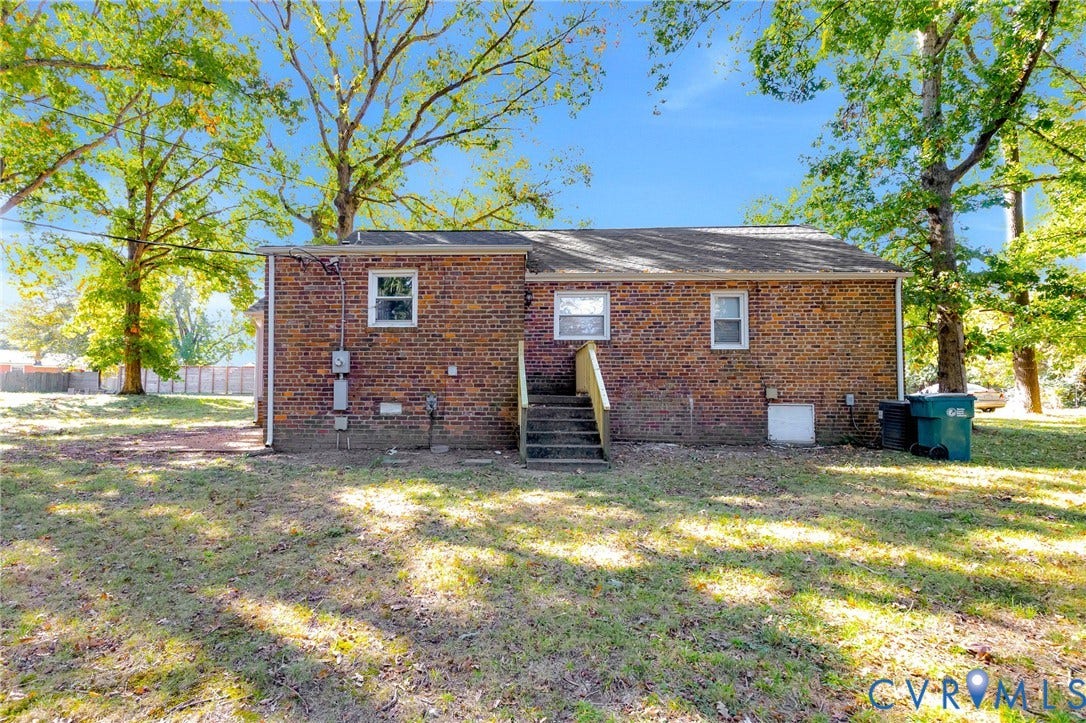 7304 Bowler Street, Henrico, VA 23228 Full brick exterior featuring a shingle roof, wood stair entry, and mature trees on a level lot