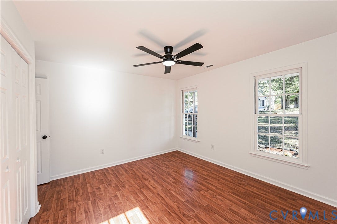 10100 Brittonwood Drive, Chesterfield, VA 23237 Interior room featuring wood-finish flooring, two double-hung windows, and a matte black ceiling fan with integrated lighting