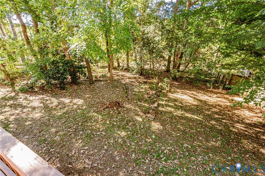 10100 Brittonwood Drive, Chesterfield, VA 23237 Spacious backyard featuring mature trees, natural landscape, and a tiered stone retaining wall