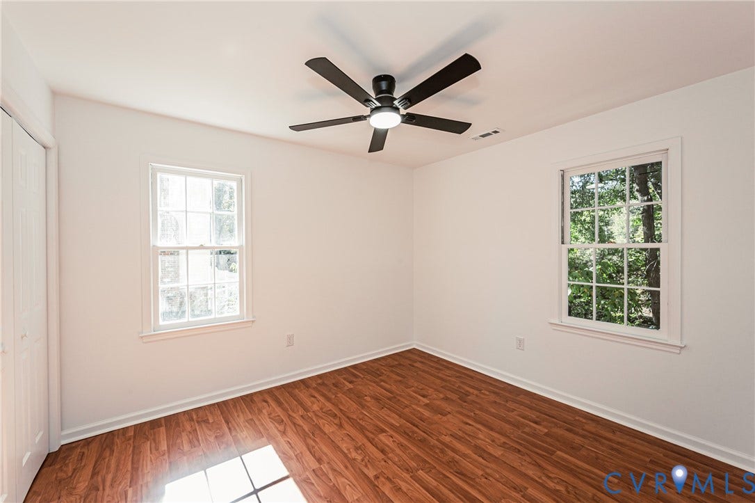 10100 Brittonwood Drive, Chesterfield, VA 23237 Interior space featuring wood-finish flooring, two double-hung windows with muntin detailing, and a central ceiling fan with integrated lighting