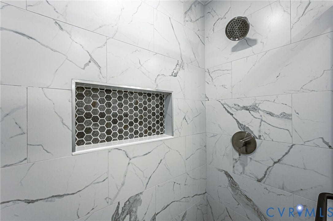 10100 Brittonwood Drive, Chesterfield, VA 23237 Shower featuring large-format tile with veining, an integrated recessed wall niche with hexagonal mosaic tile inlay, and polished metallic fixtures