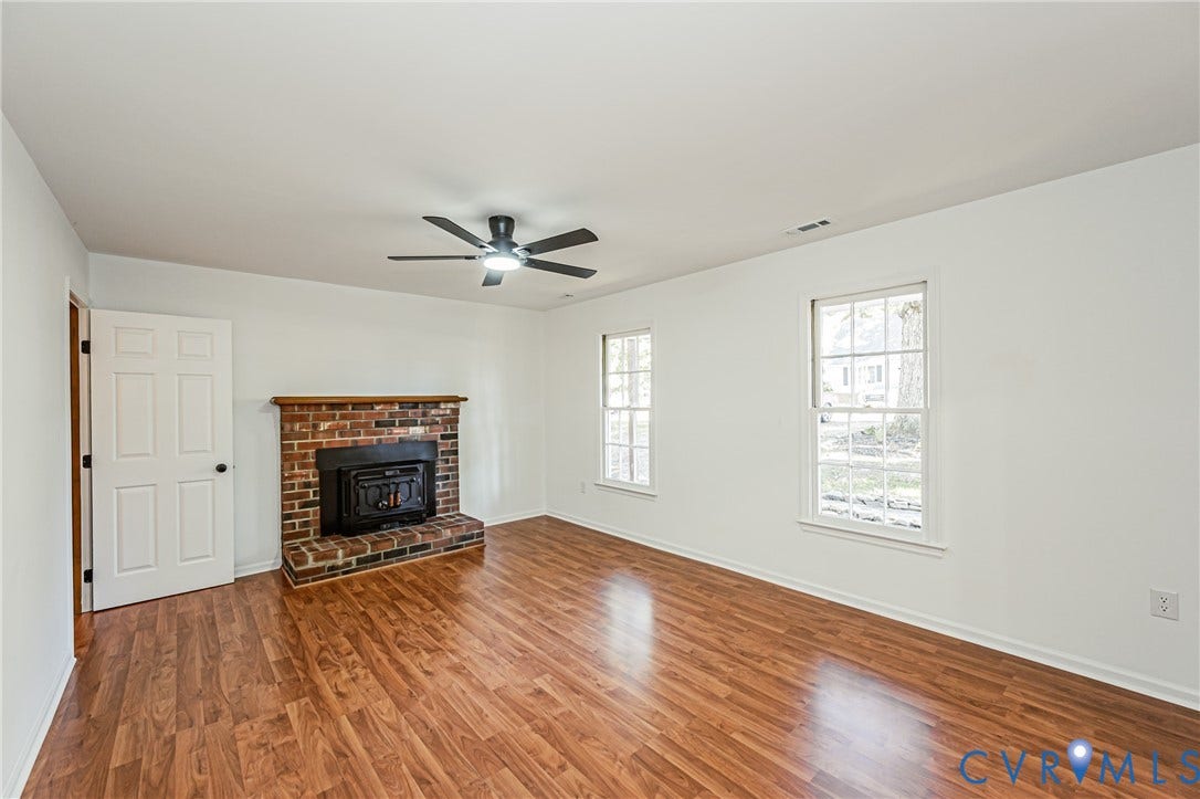 10100 Brittonwood Drive, Chesterfield, VA 23237 Living space featuring wood-finish flooring, a red brick fireplace with a wood mantle, a ceiling-mounted light fixture with fan, and double-hung windows