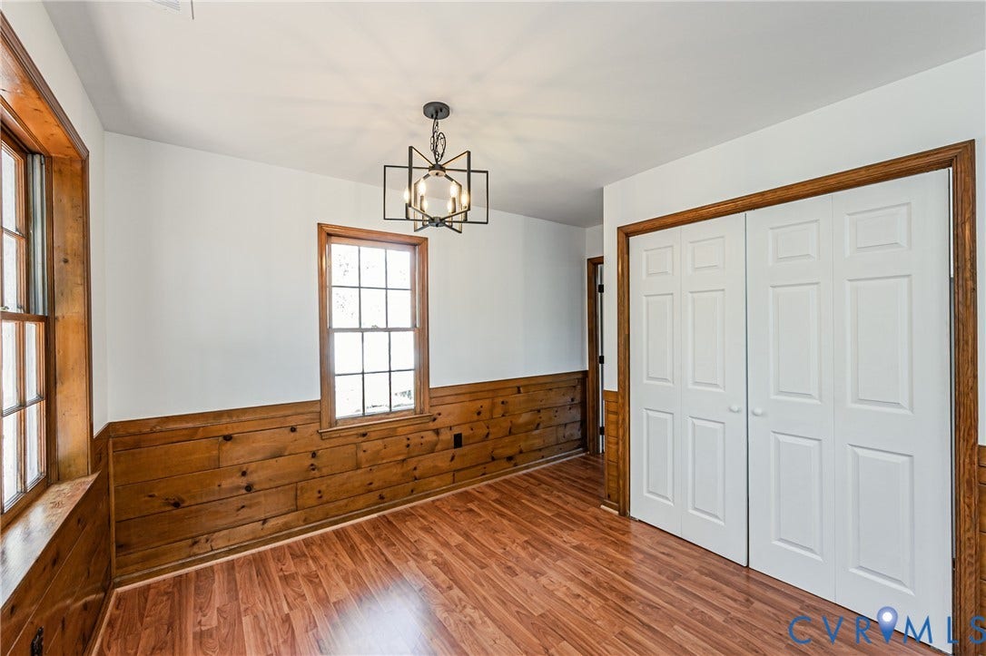 10100 Brittonwood Drive, Chesterfield, VA 23237 Room featuring wood-finish flooring, half-wall wood paneling, multi-pane windows with wood trim, six-panel closet doors, and a geometric-style metal pendant light fixture