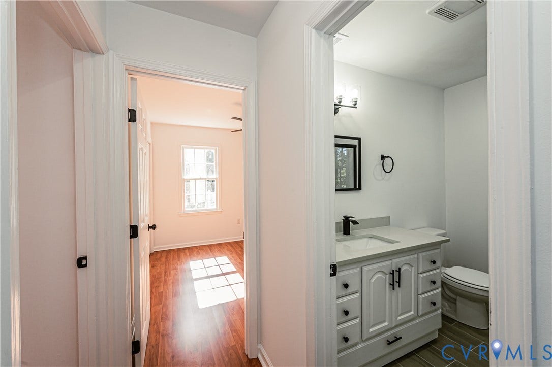 10100 Brittonwood Drive, Chesterfield, VA 23237 Bathroom featuring a white vanity cabinet with matte black hardware, stone-surface countertop, rectangular undermount sink, and dark-toned floor tiling
