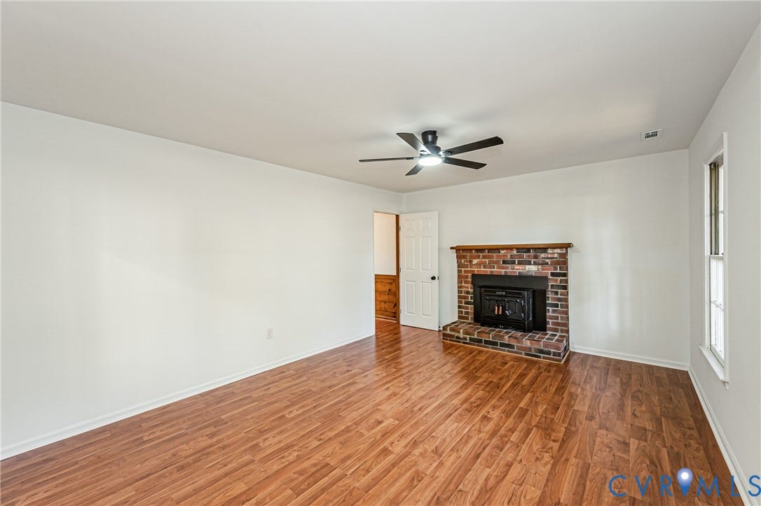 10100 Brittonwood Drive, Chesterfield, VA 23237 Brick fireplace with a wood mantel, wood-finish flooring, and a ceiling fan with integrated lighting