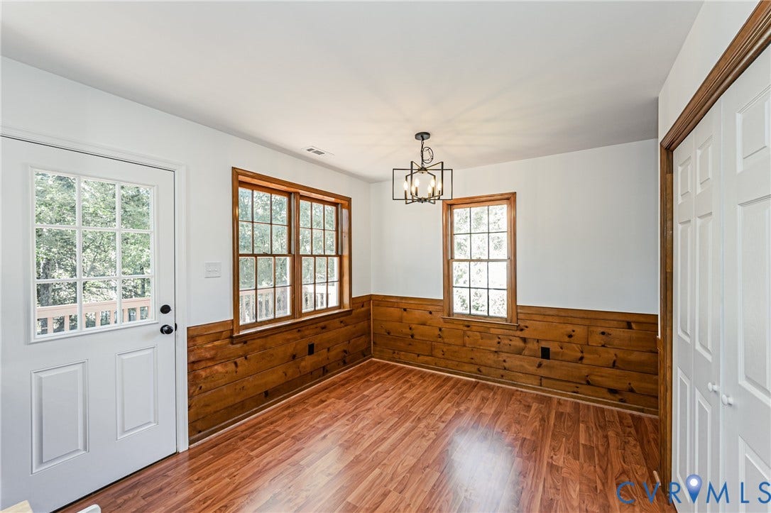 10100 Brittonwood Drive, Chesterfield, VA 23237 Wood-finish flooring, half-wall wood paneling, multi-pane windows with wood trim, six-pane glass entry door, and a geometric-style metal pendant light fixture