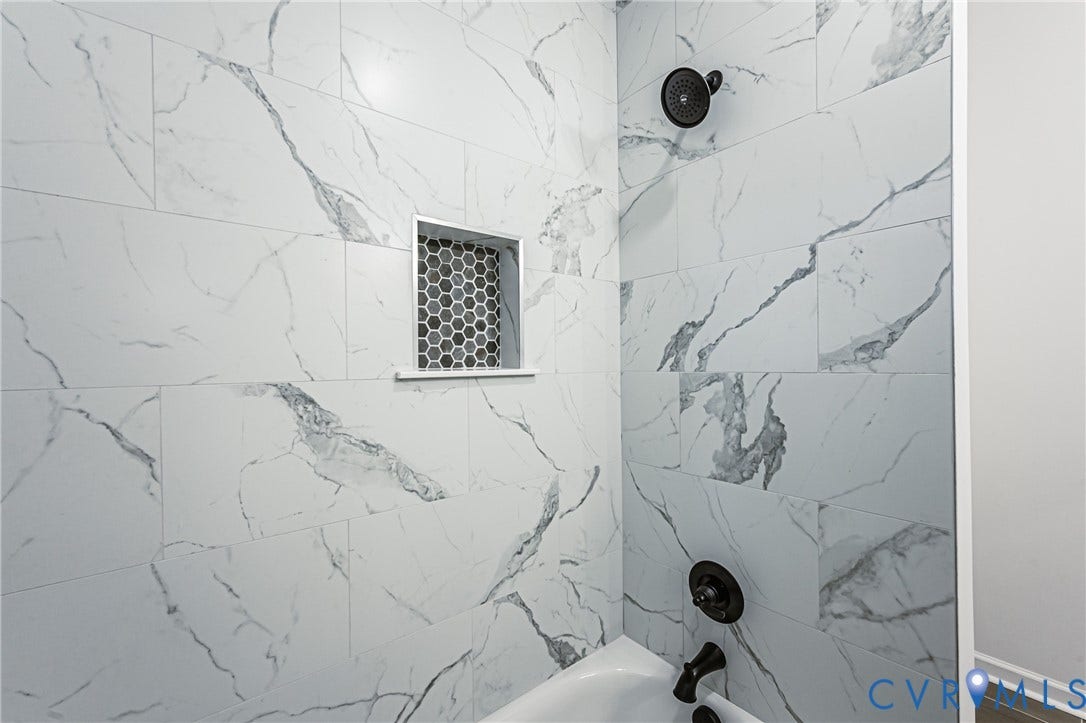 10100 Brittonwood Drive, Chesterfield, VA 23237 Shower area featuring floor-to-ceiling large-format veined tile, integrated hexagonal tile niche, matte black fixed shower head, and matching matte black wall-mounted faucet controls
