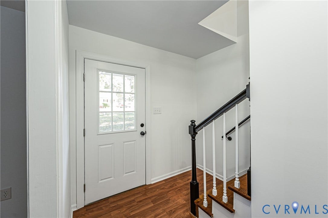 10100 Brittonwood Drive, Chesterfield, VA 23237 Entryway featuring a white door with a six-pane window insert, wood-finish flooring, and a staircase with white spindles, black handrails, and wood-finish treads