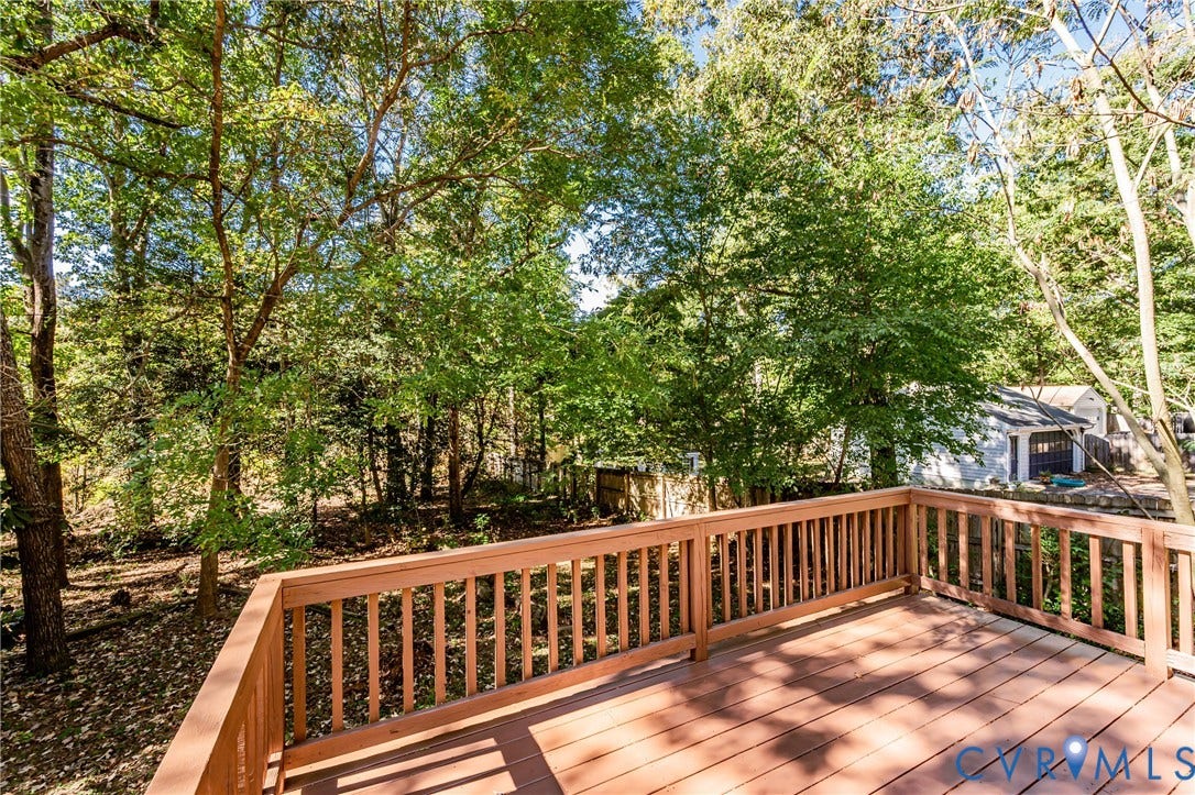 10100 Brittonwood Drive, Chesterfield, VA 23237 Elevated wood deck featuring vertical slat railings, wood-finish flooring, and mature surrounding trees
