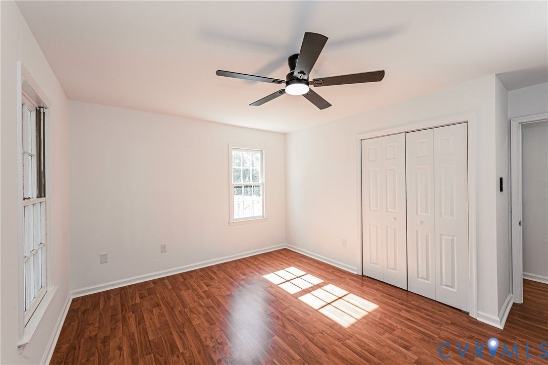 10100 Brittonwood Drive, Chesterfield, VA 23237 Interior space featuring wood-finish flooring, white walls, dual-panel closet doors, double-hung windows, and a matte black ceiling fan with integrated lighting