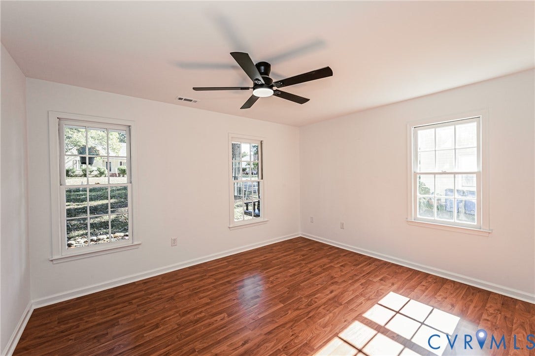 10100 Brittonwood Drive, Chesterfield, VA 23237 Room featuring wood-finish flooring, three double-hung windows with grid detailing, and a black ceiling fan with integrated lighting