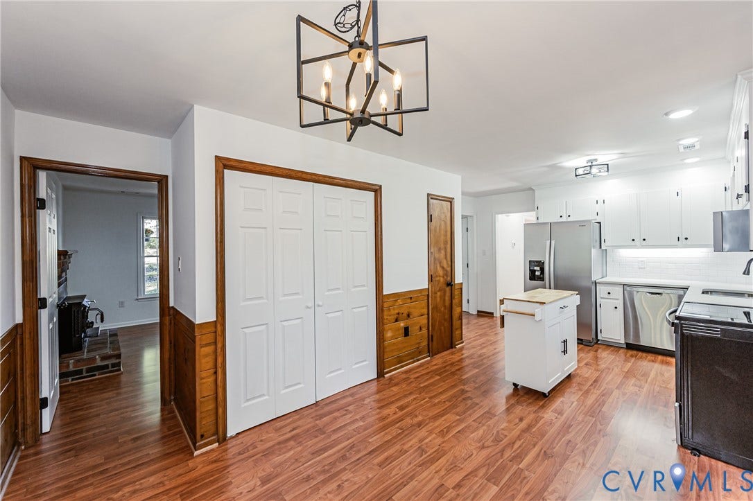 10100 Brittonwood Drive, Chesterfield, VA 23237 Kitchen featuring wood-finish flooring, half-wall wainscoting, white cabinetry, stainless steel appliances, and a geometric chandelier