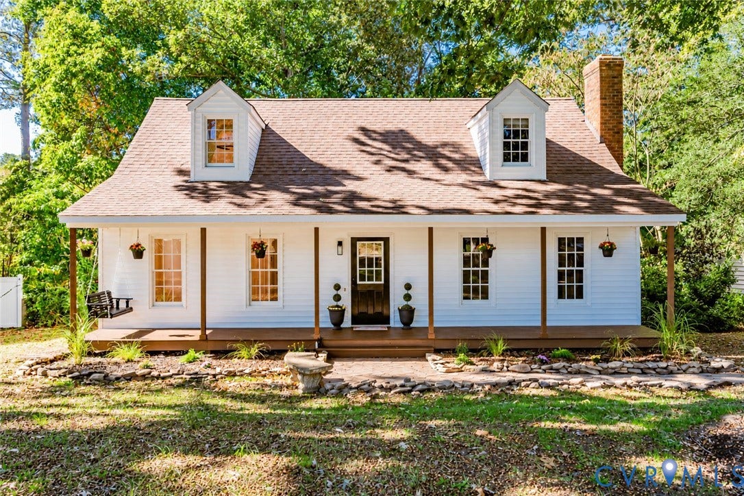 10100 Brittonwood Drive, Chesterfield, VA 23237 Cape Cod style exterior featuring white siding, a covered front porch with wood decking, dual dormer windows, and a masonry chimney