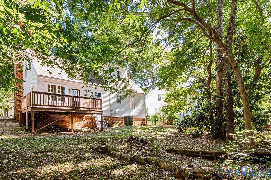 10100 Brittonwood Drive, Chesterfield, VA 23237 Rear elevation featuring a multi-level wood deck, white vinyl siding, brick foundation, and mature canopy trees