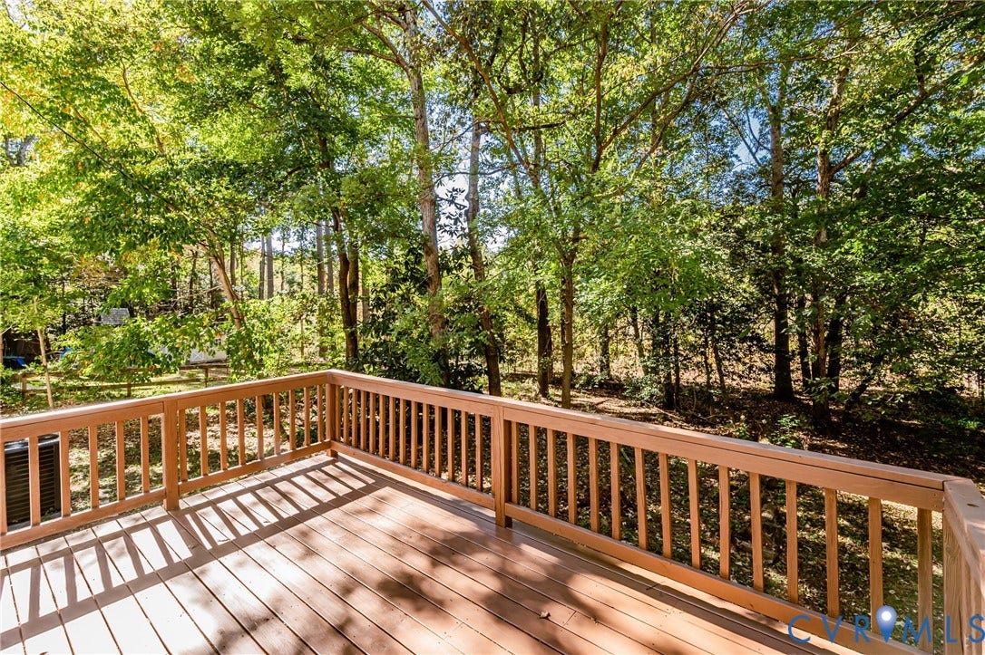 10100 Brittonwood Drive, Chesterfield, VA 23237 Elevated wooden deck featuring wood-finish flooring, a perimeter railing, and mature tree-lined surroundings