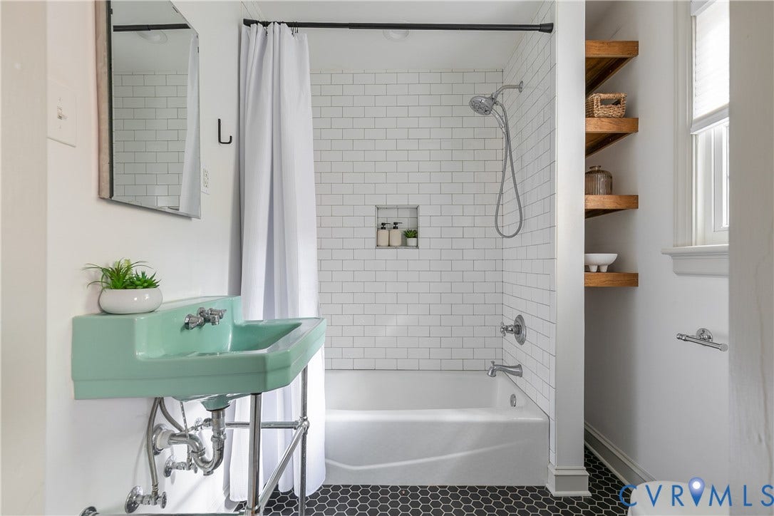 4710 Park Avenue, Mary Munford / Near West End, Richmond, VA 23226 Wall-mounted console sink with exposed plumbing, white subway tile shower surround with integrated soap niche, black hexagonal floor tile, and wood-finish built-in shelving