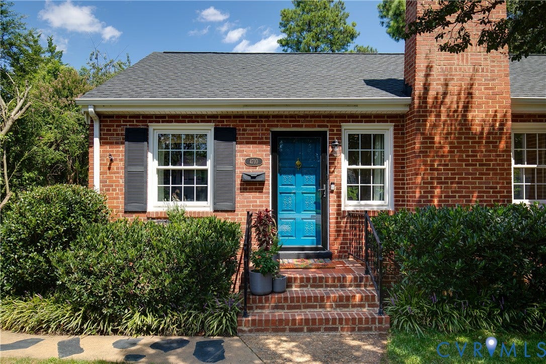4710 Park Avenue, Mary Munford / Near West End, Richmond, VA 23226 Red brick exterior featuring a blue paneled front door, an external brick chimney, dark shutters, and tiered brick entryway steps with iron handrails