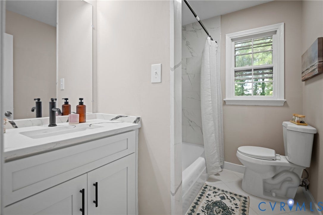 9010 Fawn Lane, Henrico, VA 23229 Bathroom featuring a white vanity with a stone-top integrated sink, matte black hardware, large wall-mounted mirror, and a shower-tub combination with white tile surround