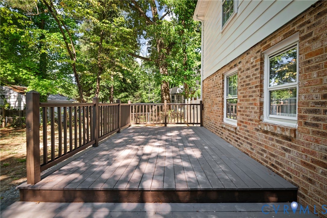 9010 Fawn Lane, Henrico, VA 23229 Ground-level composite deck with a dark-toned railing, exterior brick veneer, light-colored horizontal siding, and multiple double-hung windows
