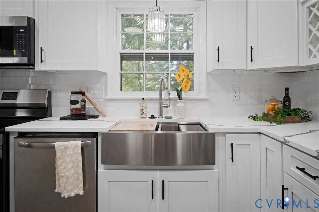 9010 Fawn Lane, Henrico, VA 23229 White cabinetry featuring black hardware, stainless steel farmhouse sink with gooseneck faucet, light-toned countertops, subway tile backsplash, and built-in stainless steel appliances