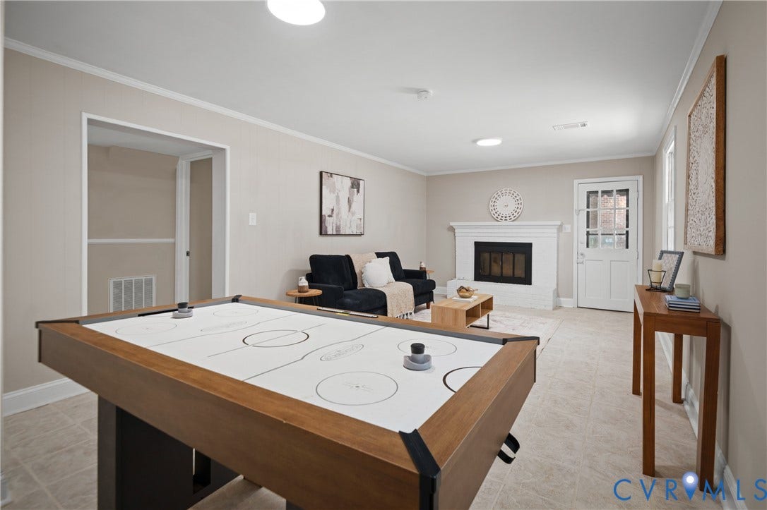 9010 Fawn Lane, Henrico, VA 23229 Neutral-toned interior space featuring a white fireplace with a prominent mantel, tile flooring, and a glass-paneled exterior door