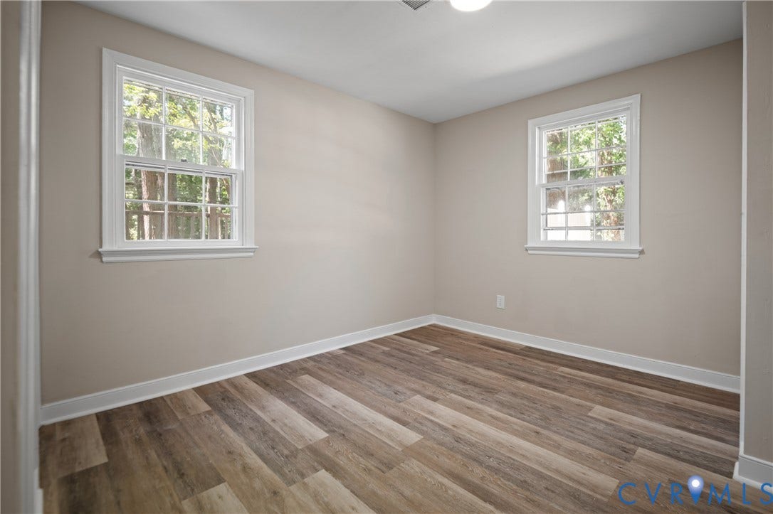 9010 Fawn Lane, Henrico, VA 23229 Neutral-toned interior space featuring wood-finish flooring, two double-hung windows with muntins, and a ceiling-mounted light fixture