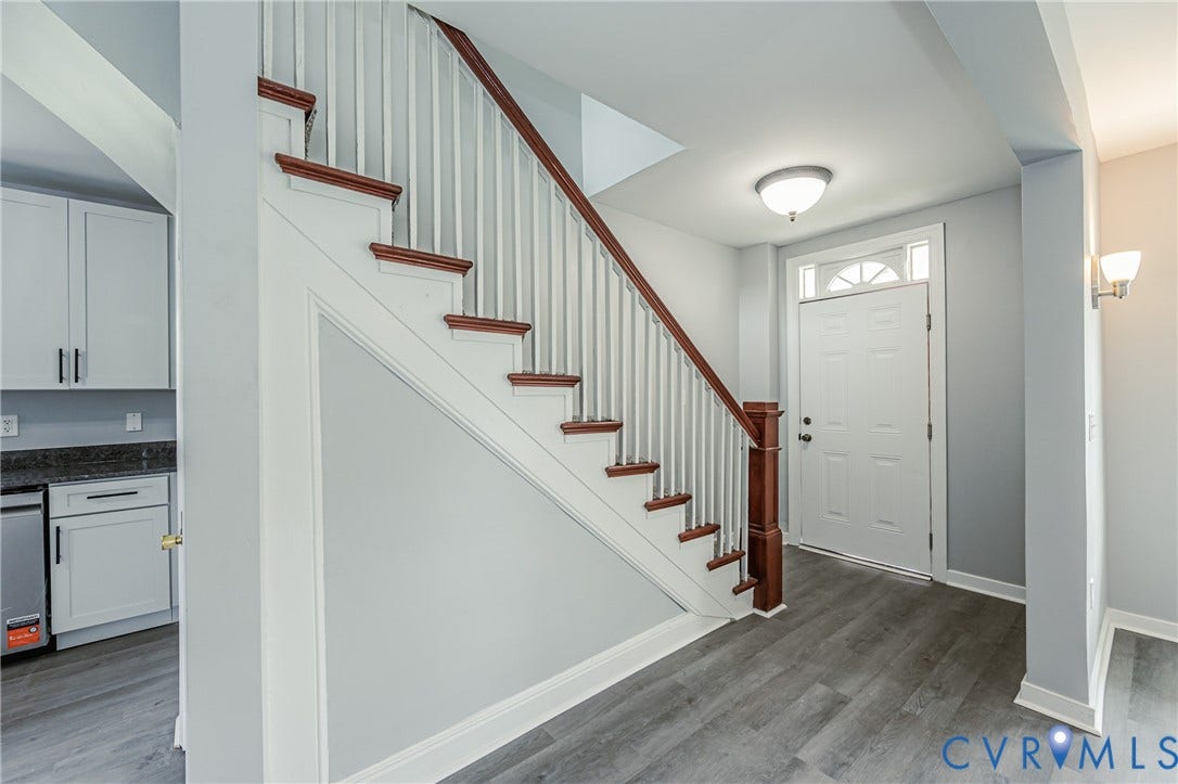 Staircase featuring wood treads and a white balustrade, wood-finish flooring, white panel door with transom window, and flush-mount ceiling lighting