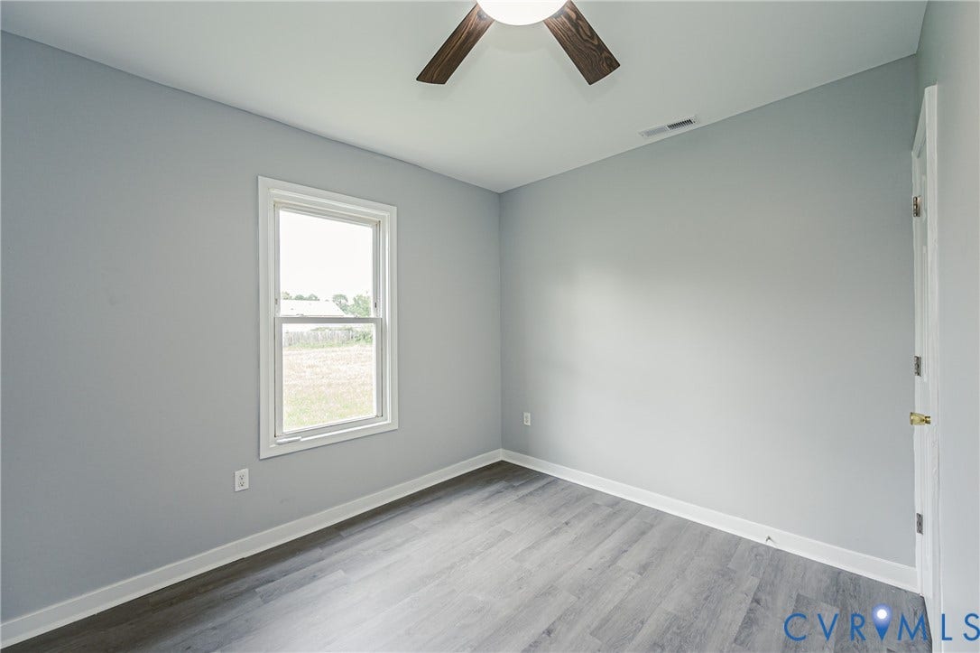 Neutral-toned interior featuring wood-finish flooring, a ceiling fan with integrated lighting, and a single-hung window