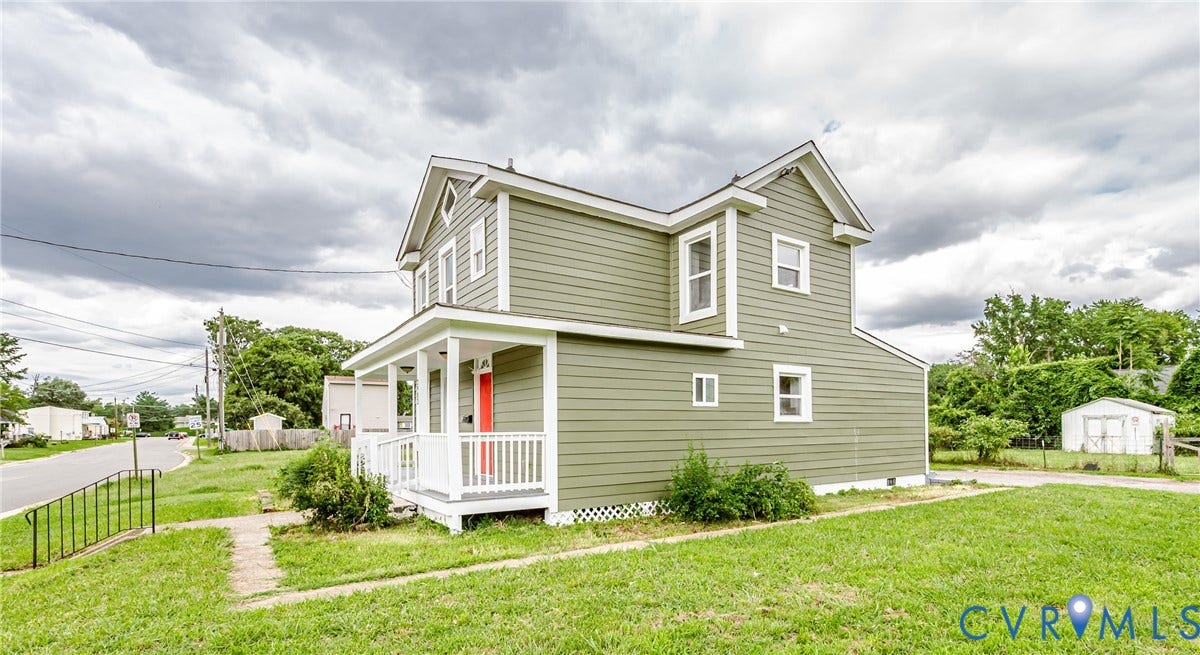 Two-story residence featuring sage green siding, a covered front porch with white railing, and a gabled roofline