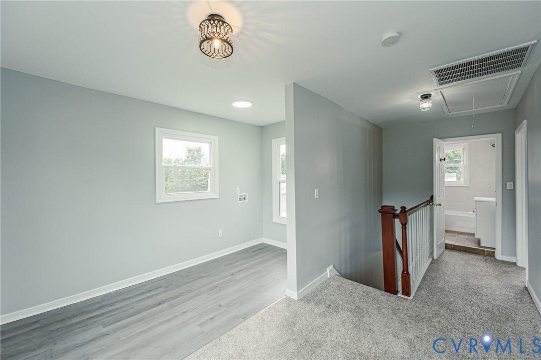 Wood-finish flooring, neutral wall tones, decorative metal ceiling fixtures, integrated recessed lighting, and a stained-wood stair railing