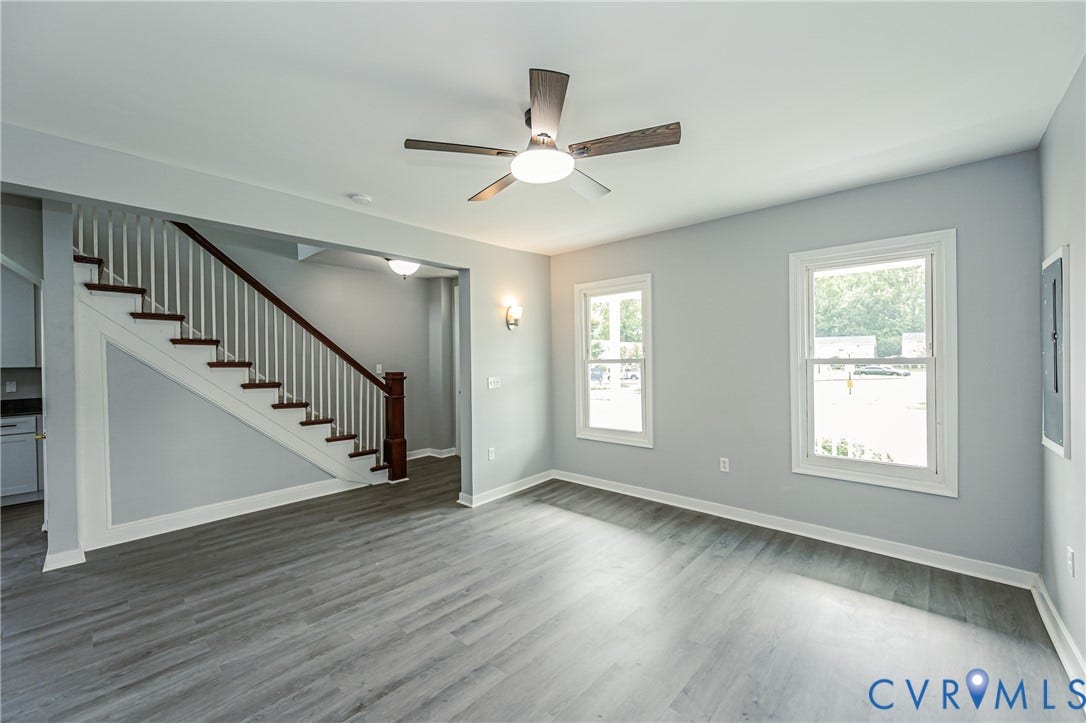 Wood-finish flooring, staircase with a dark-stained handrail and white balusters, recessed lighting, ceiling fan with light kit, and multi-pane windows