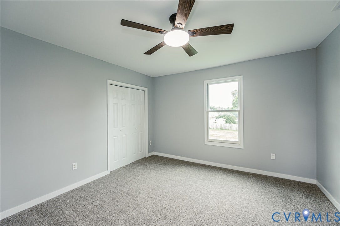 Neutral-toned wall paint, wall-to-wall carpeting, ceiling fan with integrated lighting, and dual-panel closet doors